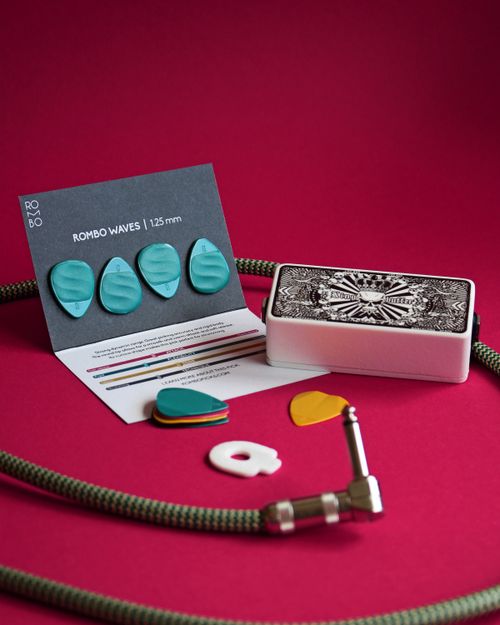 Free Assorted guitar picks and cable on vibrant red backdrop. Stock Photo
