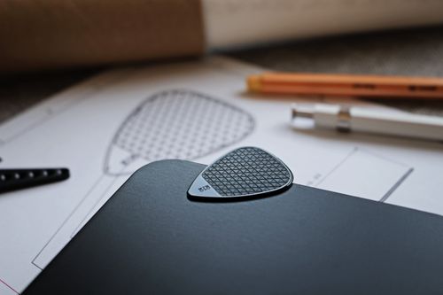 Free Close-up of a guitar pick on a design blueprint beside drafting tools. Stock Photo