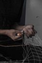 Crop black man untangling fishnet at home