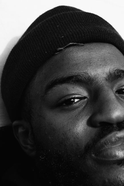Close-up black and white portrait of man wearing a beanie, showing contemplative expression.