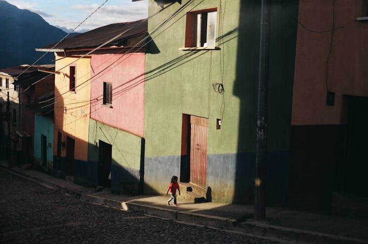 Child Walking On The Sidewalk Near Colorful Houses