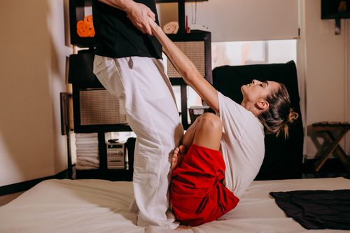 Free A woman performs assisted stretching for flexibility indoors, promoting wellness and fitness. Stock Photo