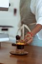 Crop barista placing cup of espresso on saucer for client