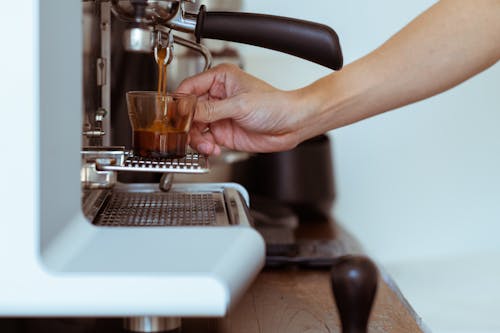 Crop barista making coffee in coffeemaker