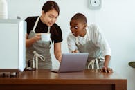 穿着围裙、使用现代上网本的多元化同事们兴高采烈地聚集在明亮舒适的厨房里，一边喝着饮料，一边在餐桌旁分享商业想法，大家都感到惊喜不已