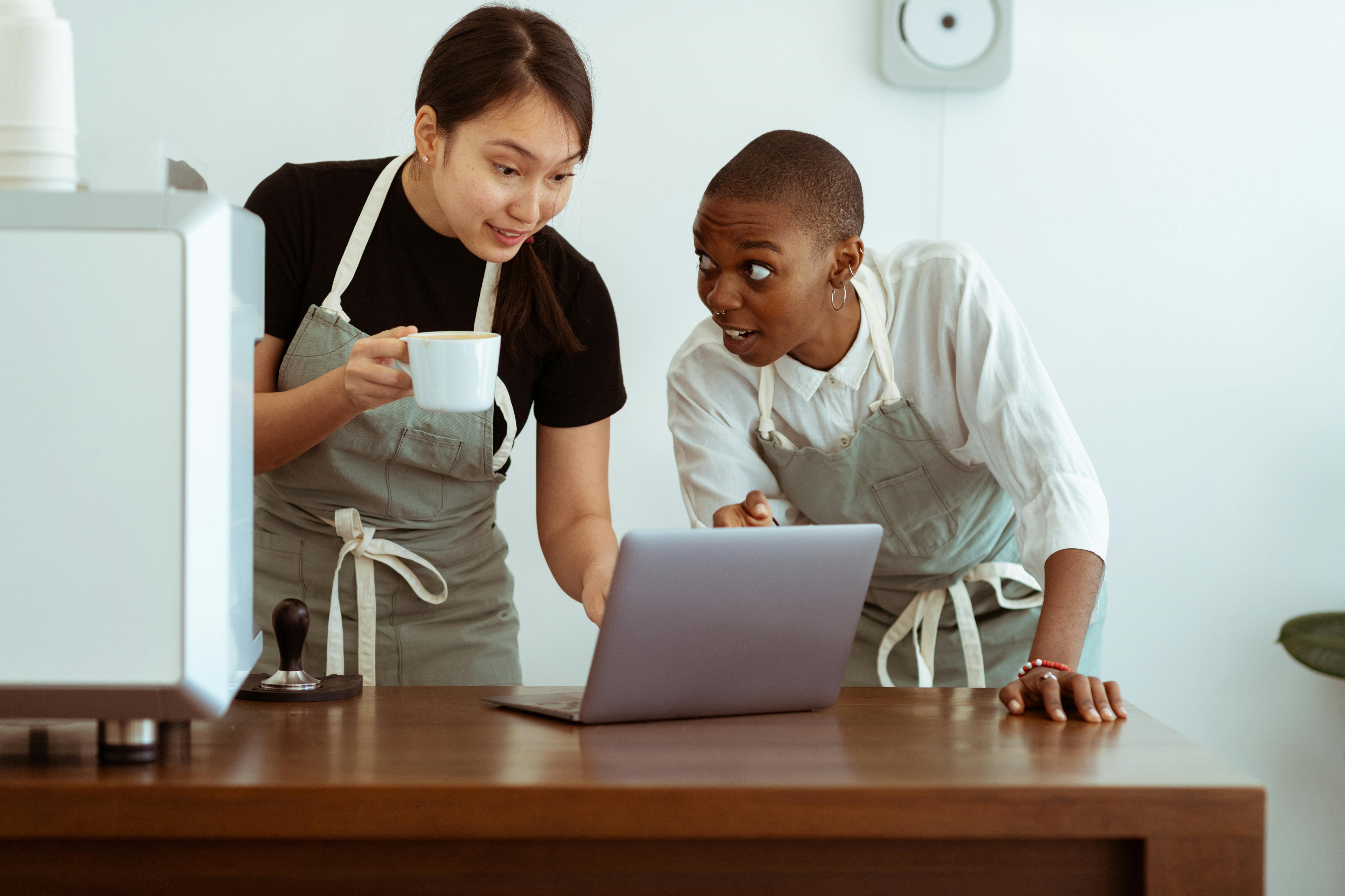 Positive waitresses working on laptop and discussing work · Free Stock Photo