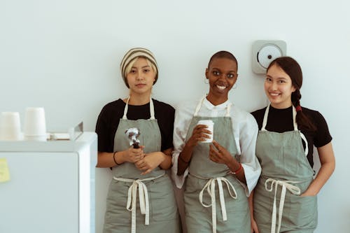 Happy waitresses with portafilter against white wall