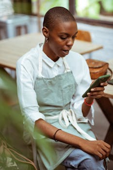Woman in a casual café setting, using her smartphone during a break.