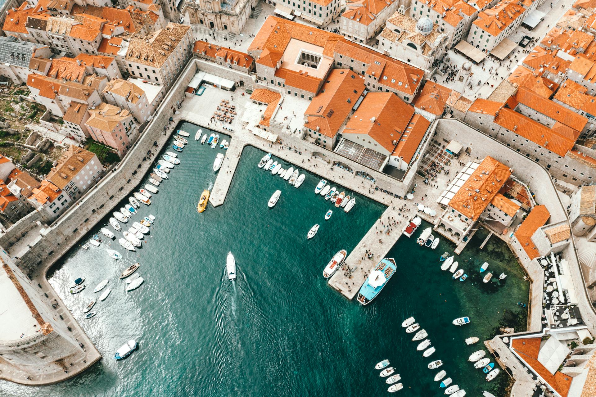 Breathtaking drone view of coastal town with traditional red roofed buildings and harbor with moored boats in Croatia