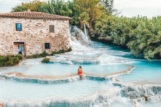 A woman relaxing at the scenic Cascate del Mulino hot springs in Tuscany, Italy.