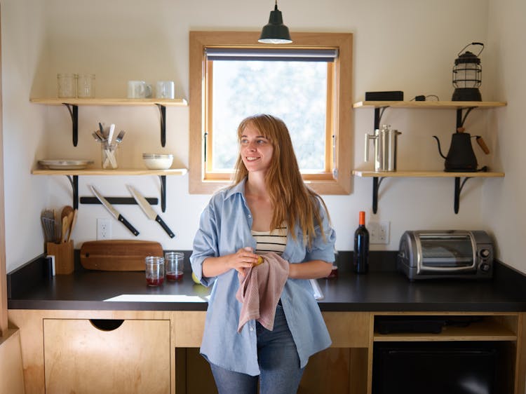 Happy Woman With Dishcloth And Apple In Kitchen