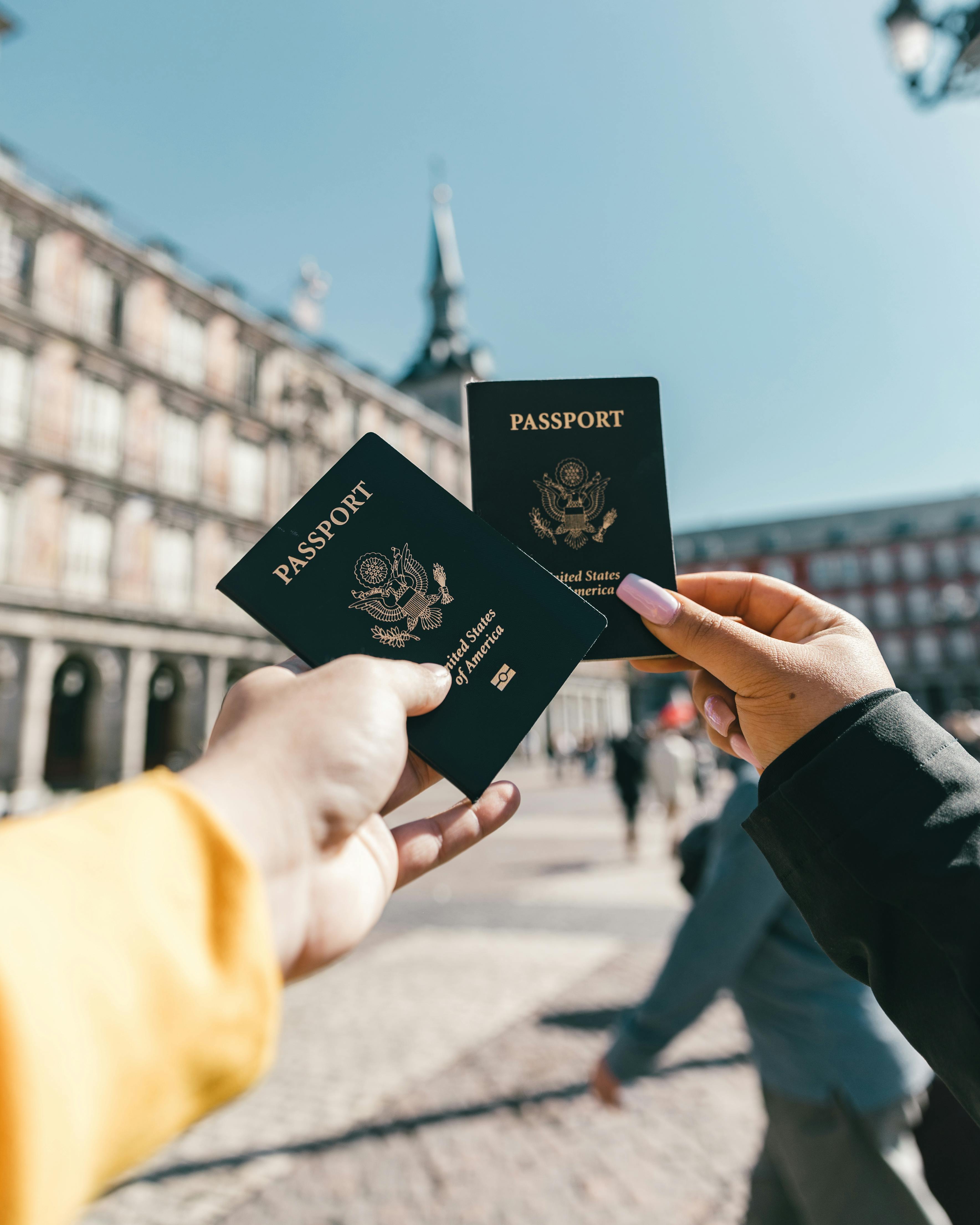 Anonymous tourists showing US passports on street on sunny day