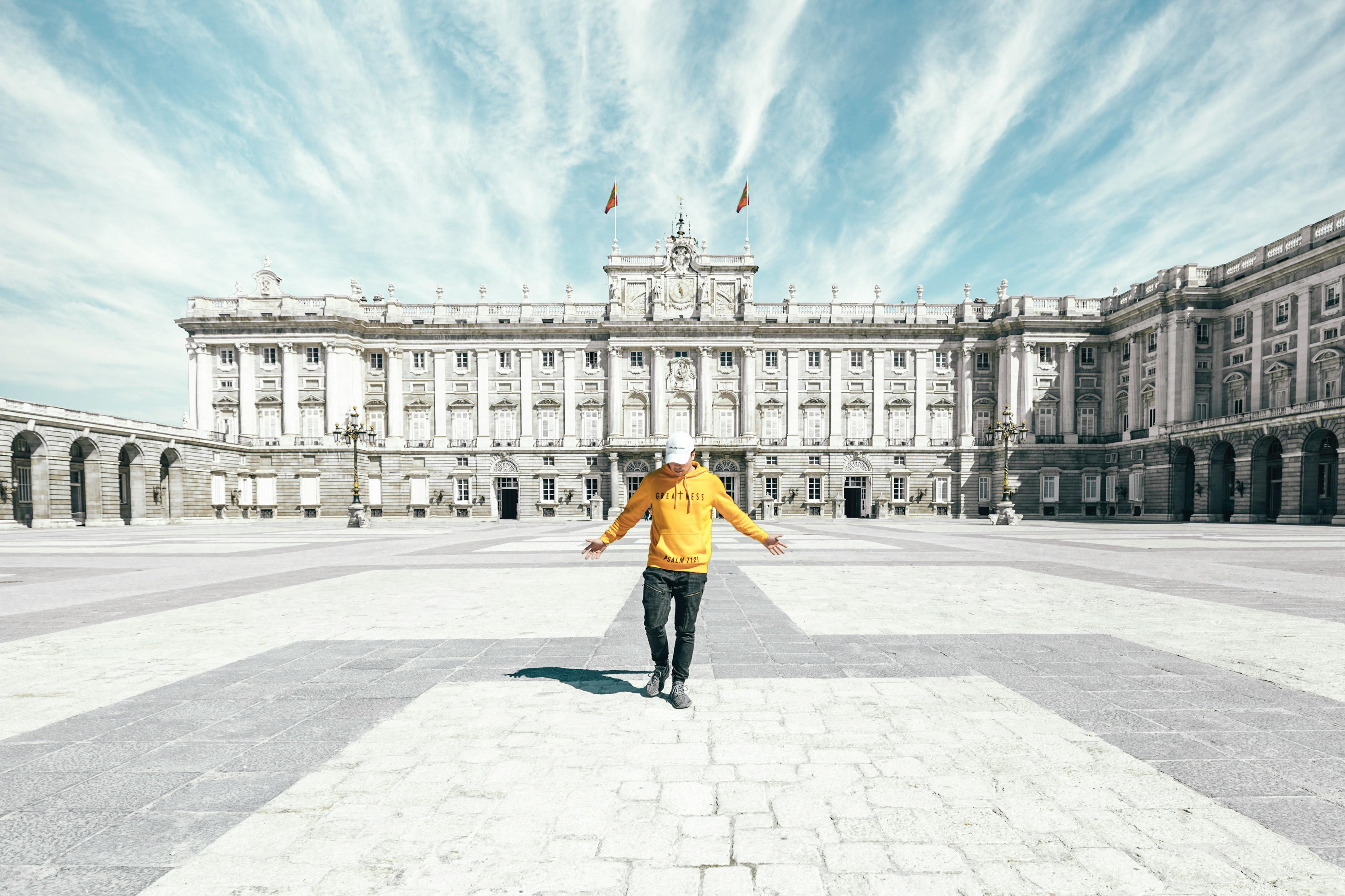 faceless tourist with outstretched arms standing alone on square near historical palace