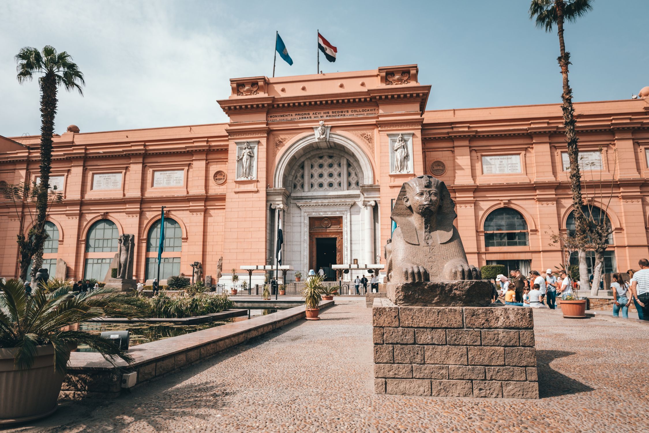 Low angle of aged building of Egyptian Museum located in Cairo with arched doorway and ancient statues in yard