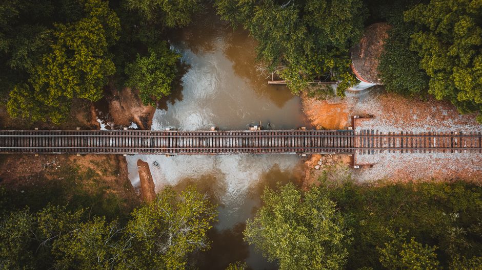 Unforgettable Helicopter Ride Over Pigeon Forge and Bluff Mountain Review 2026 - Picturesque drone view of rustic railroad going over pond in lush green forest on sunny day