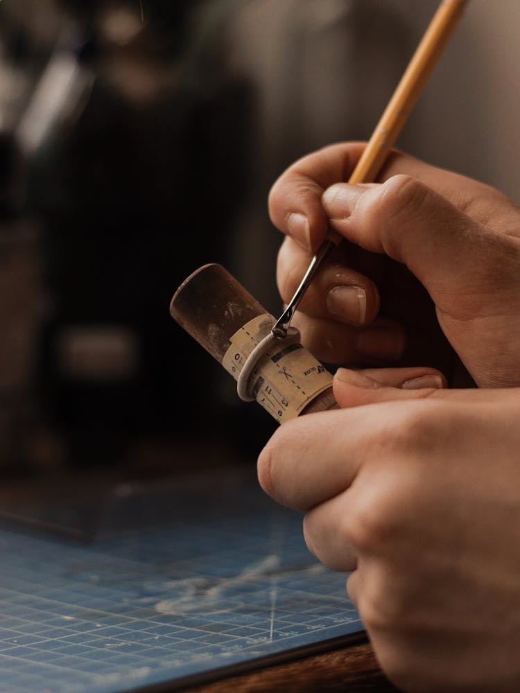 Hands Of A Person Holding A Tube And Jewelry Making Tools