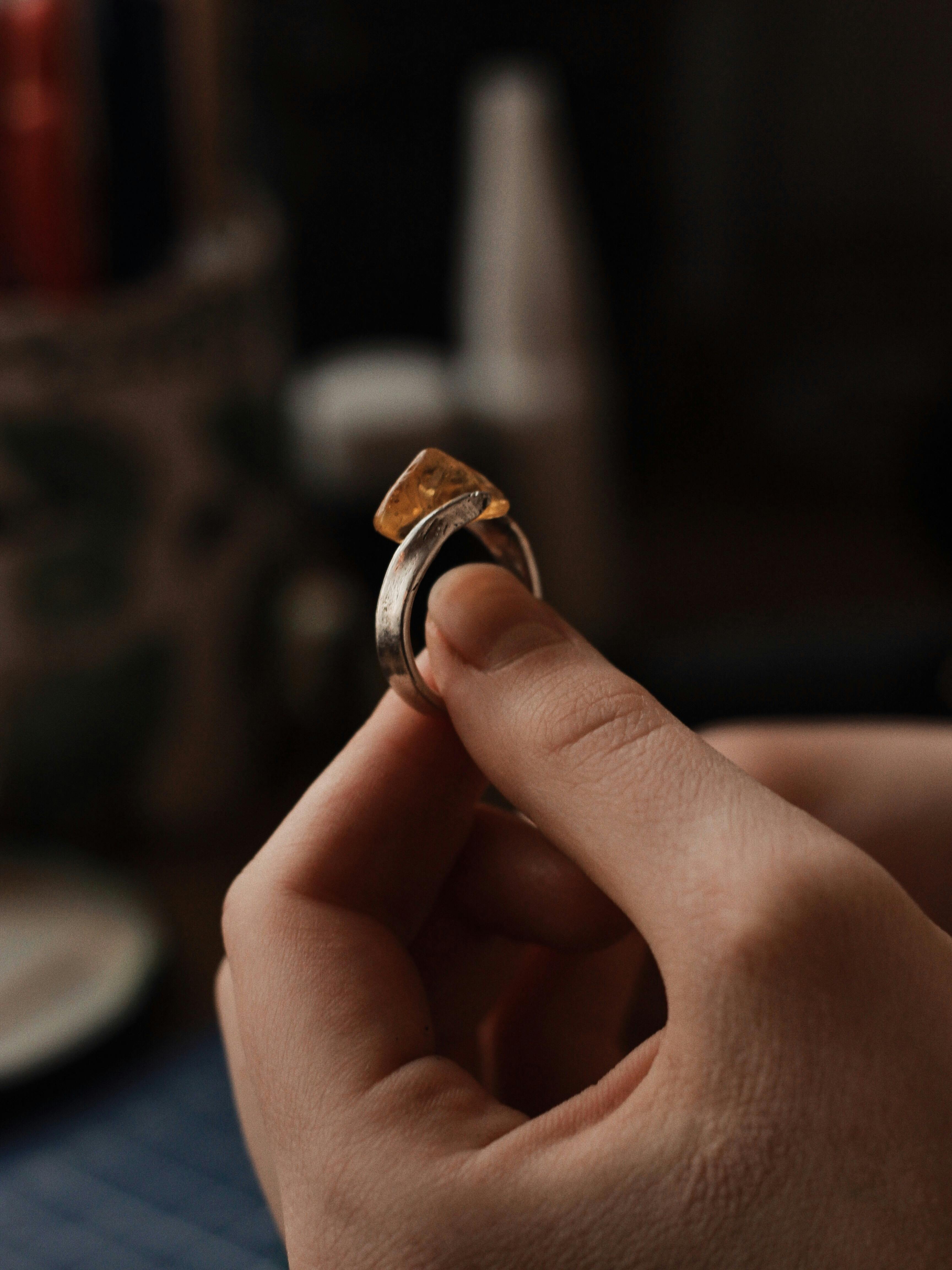 person holding silver ring with a gemstone