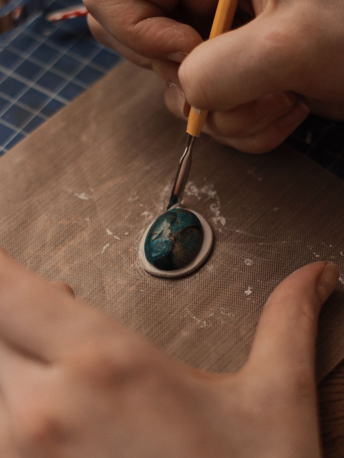 Hands performing detailed gemstone craft work