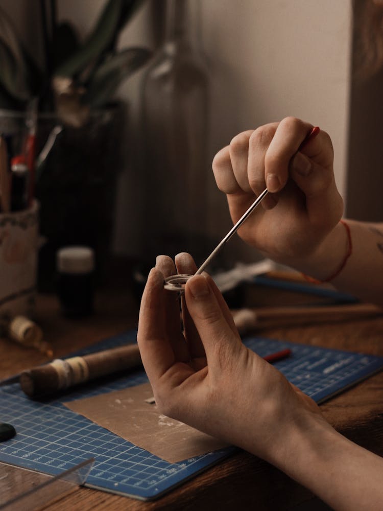 Hands Of A Person Holding A Round Object And A Silver Tool