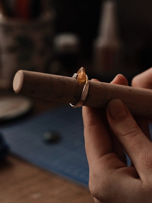 Person Holding Wooden Tool With a Silver Ring