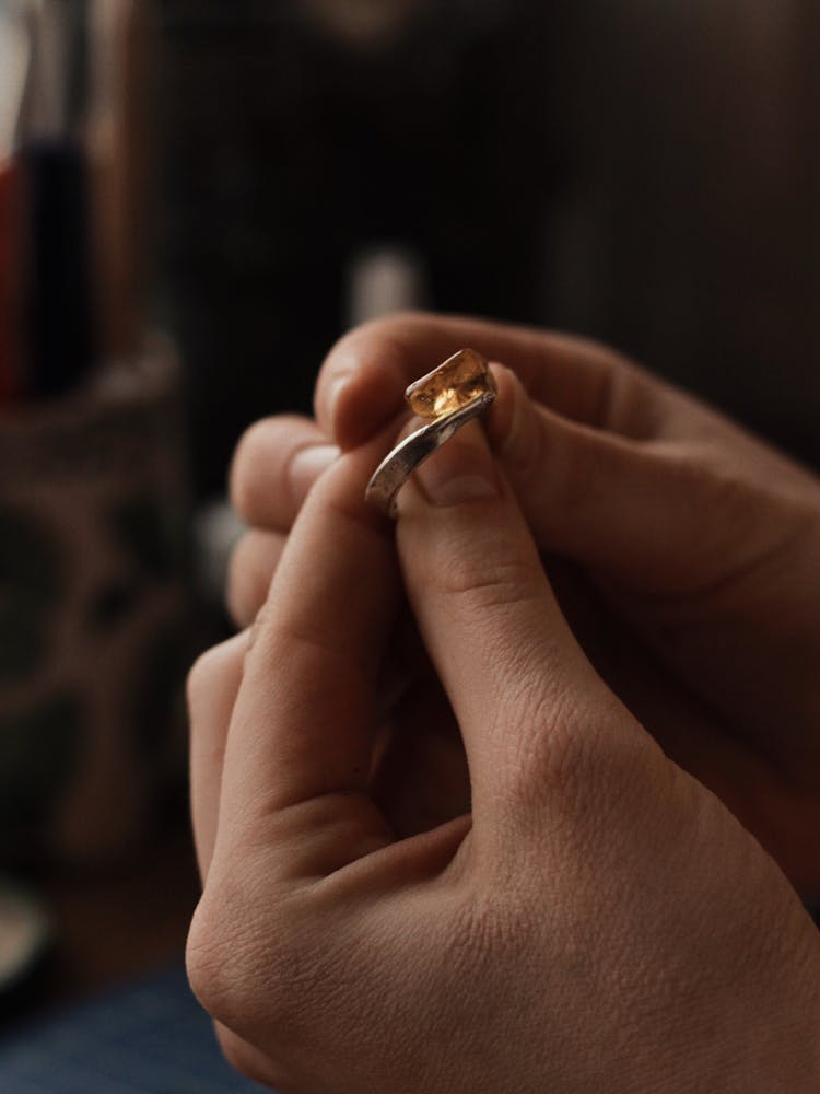 Person Holding A Silver Ring With Orange Gemstone