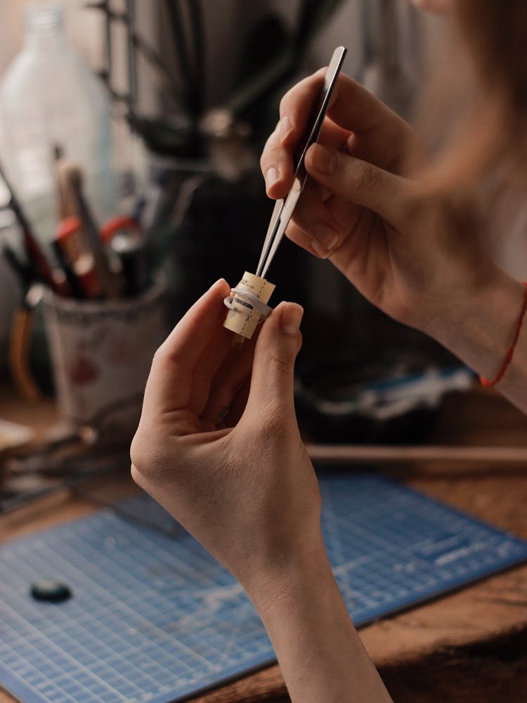 Person Holding A Tweezer And A Cylindrical Object