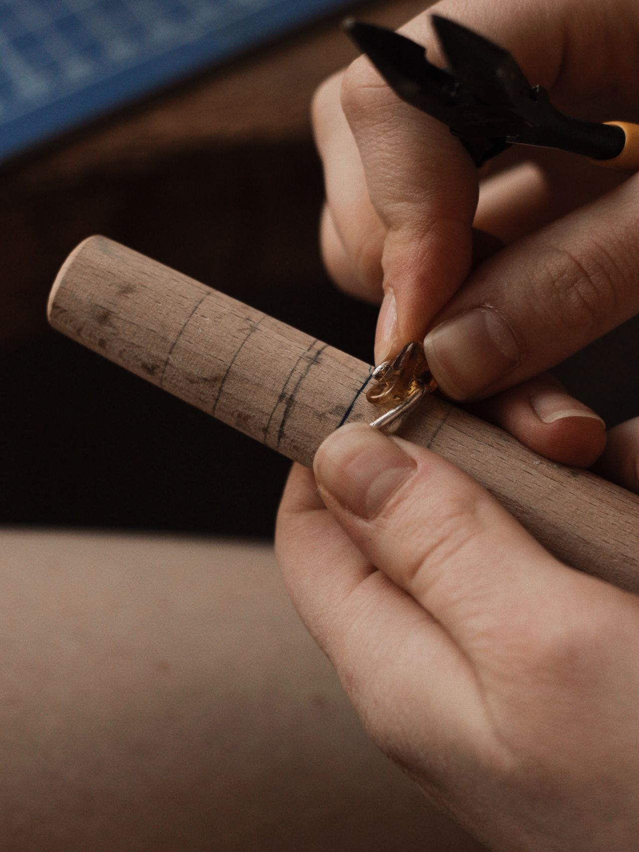 A jeweler sizing a ring on a wooden ring mandrel with pliers