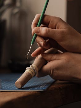 Artisan skillfully works with tools crafting jewelry on a wooden desk.
