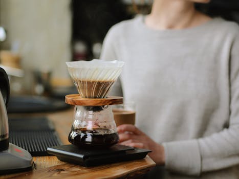Close-up of a pour over coffee brewing process in a cozy cafe with a blurred background.