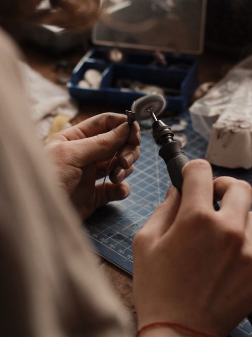 Free Close-up of a jeweler polishing silver jewelry in a workshop setting. Stock Photo