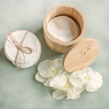 Reusable cotton pads in a bamboo container with flowers, promoting zero-waste lifestyle.