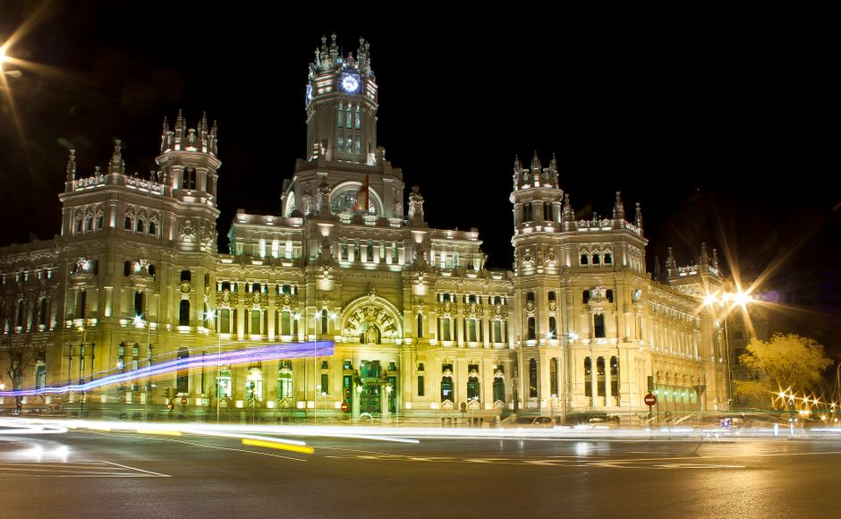 Toma nocturna de larga exposición del iluminado Palacio de Cibeles en Madrid, mostrando su arquitectura histórica.