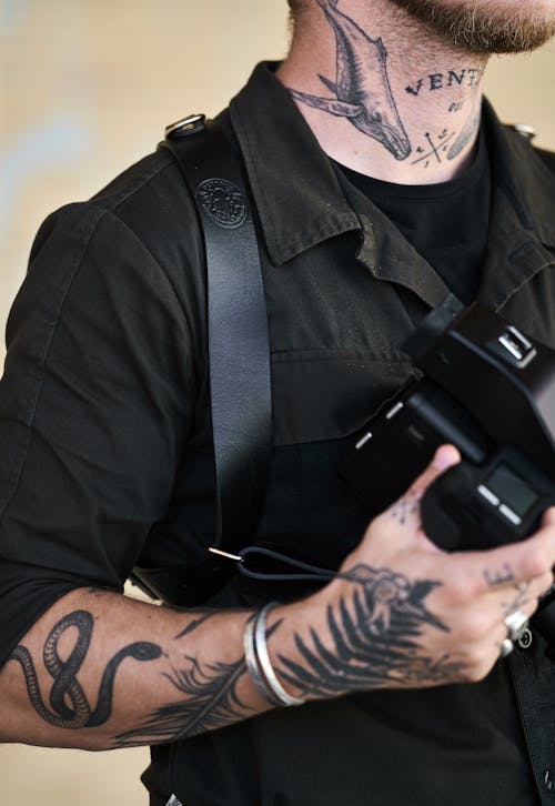 Crop tattooed photographer with photo camera