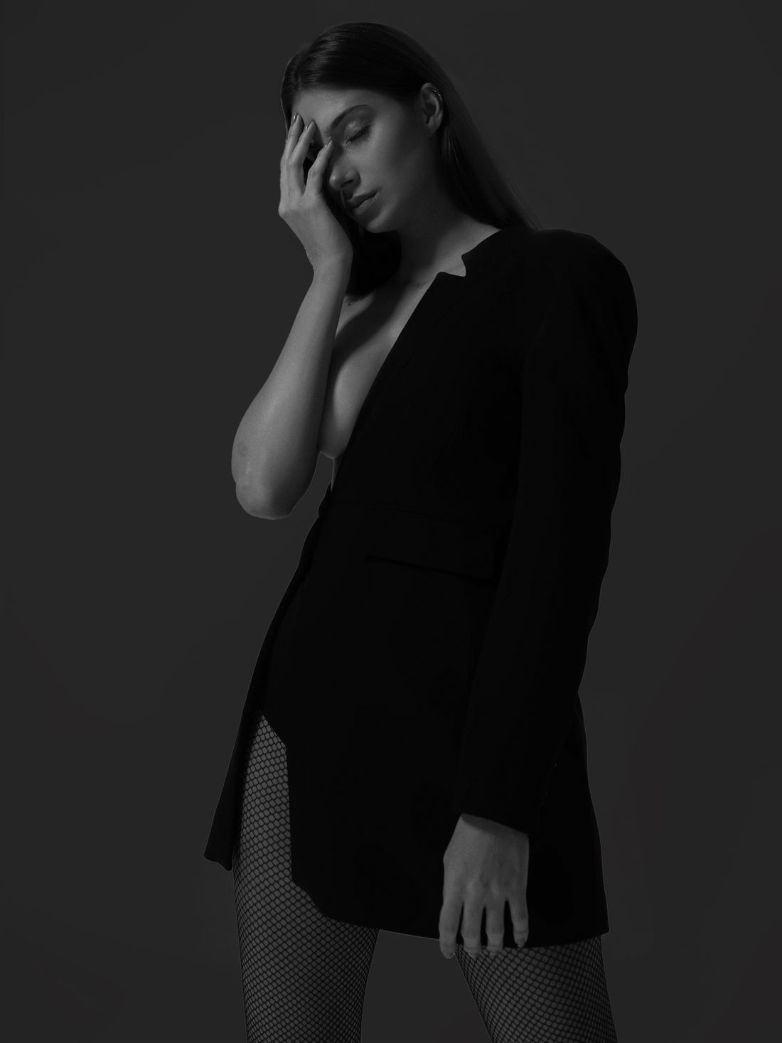 Model in a sharply cut black blazer, monochrome studio portrait