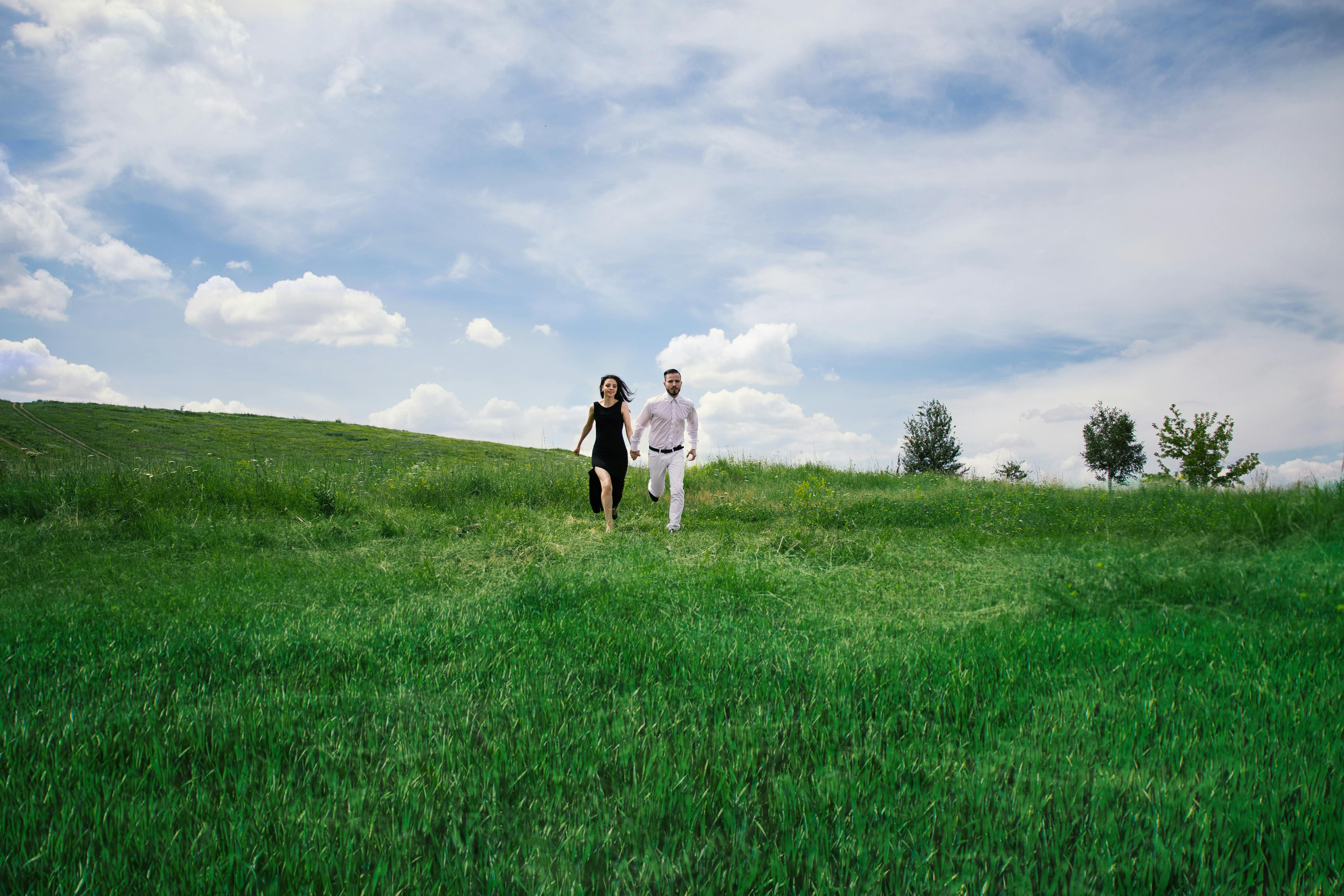 Couple running happily in field · Free Stock Photo