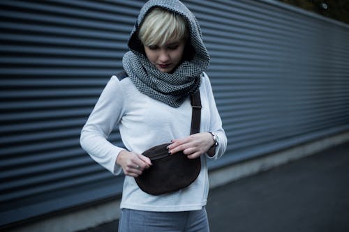 Free Pensive young woman opening bag on street Stock Photo