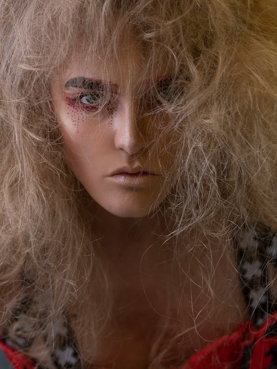 Serious young female model with messy blond hair and artistic makeup looking at camera
