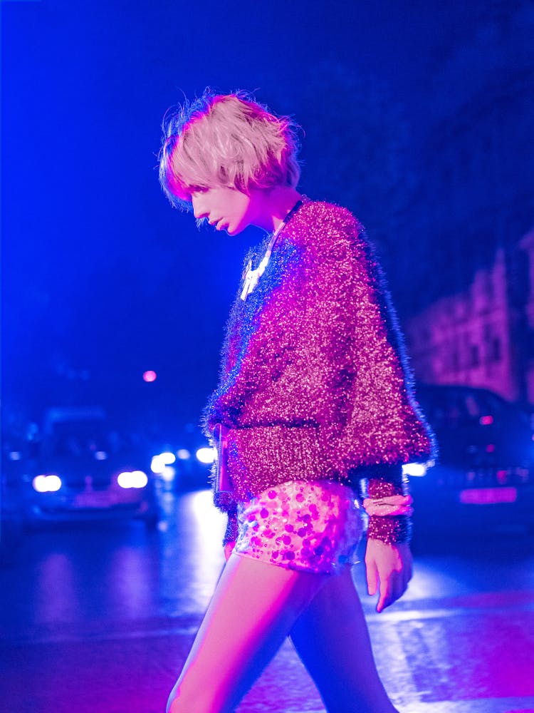 Young Woman Walking On Illuminated Street At Night