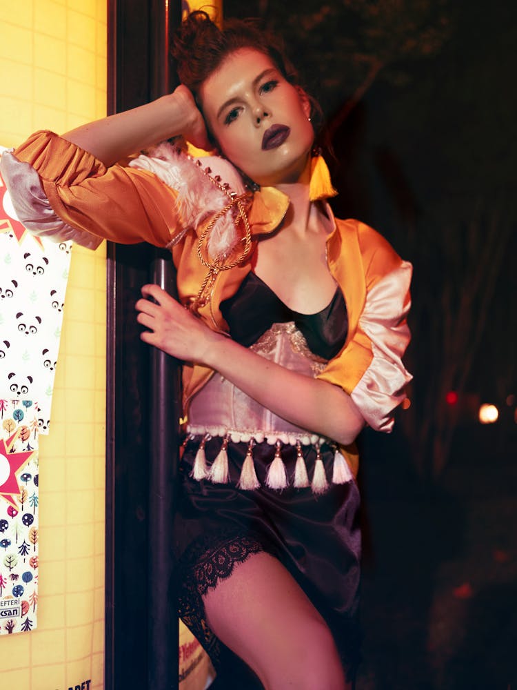 Alluring Young Female Standing On Doorstep Of Store At Night