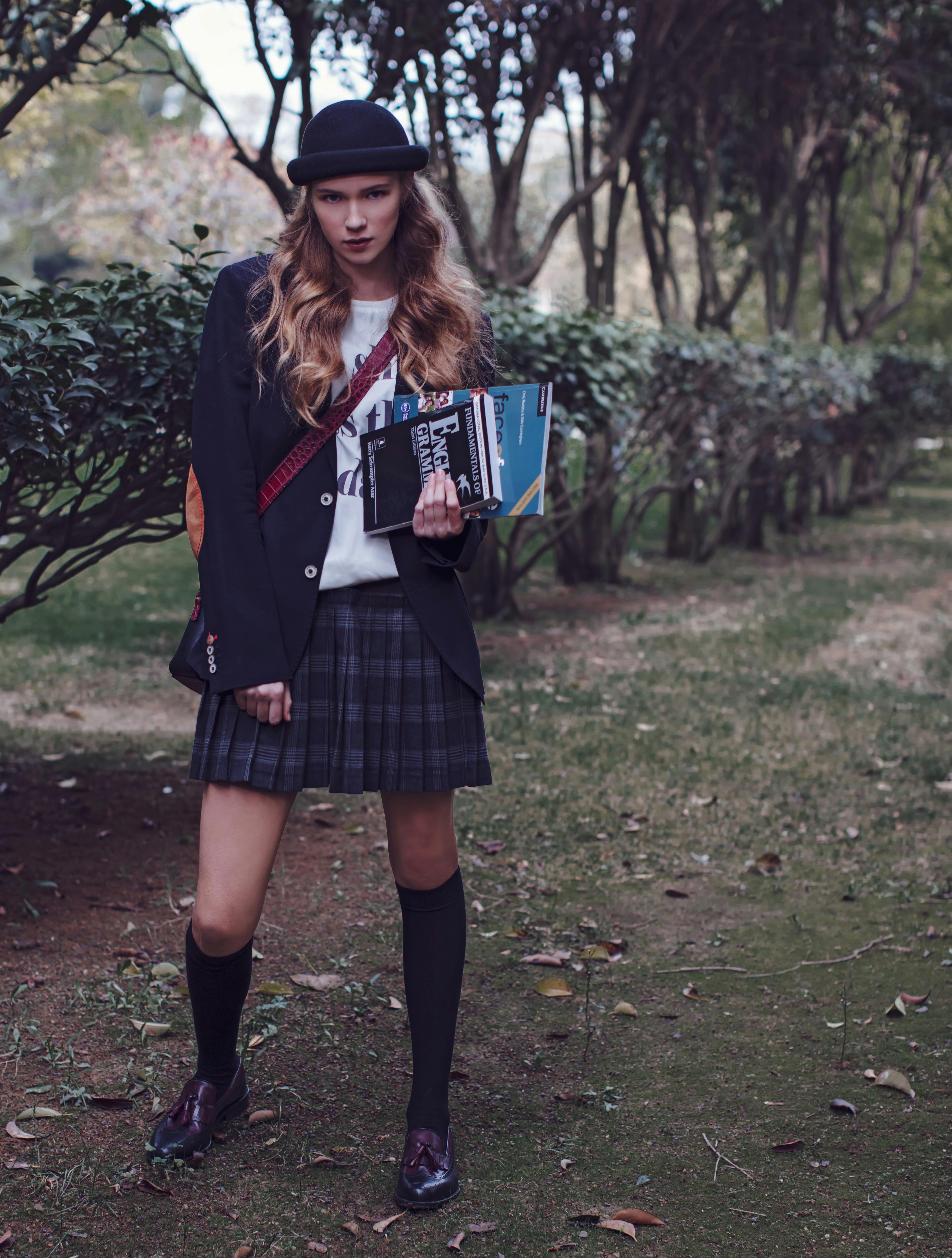 trendy young woman with books in park