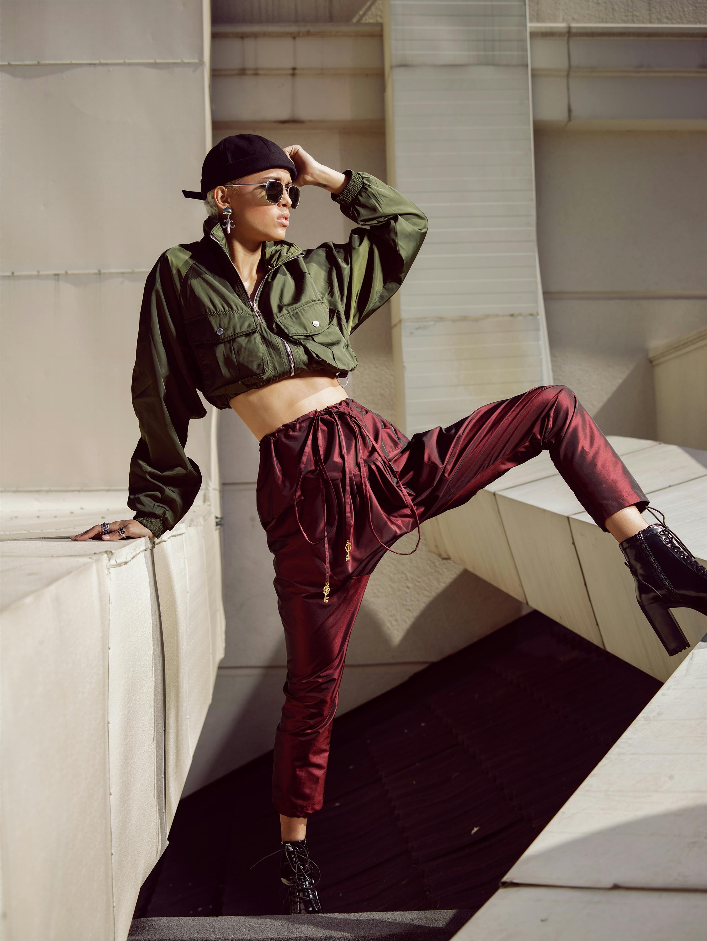 Stylish woman poses outdoors with modern architecture backdrop.