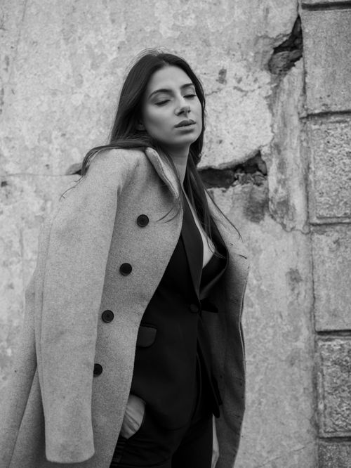 Free Portrait of an elegant woman in formal street fashion wearing a coat. Captures urban style with an artistic touch. Stock Photo