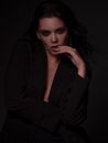 Young stylish sensual female in black outfit with flowing hair looking at camera