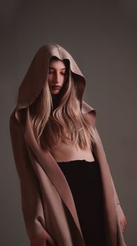 Young female with makeup and closed eyes wearing hood and covering nude breast with hair