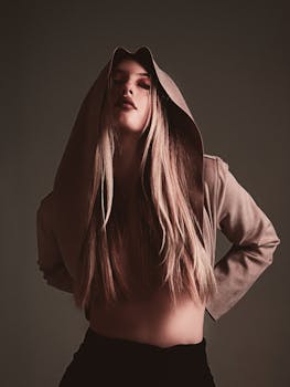 Artistic portrait of a young woman with long blonde hair in a beige hoodie, exuding contemporary fashion style.