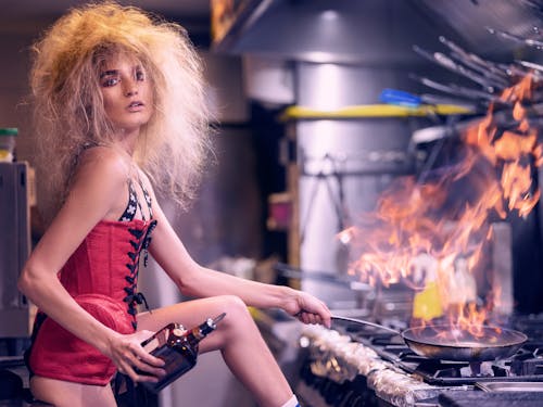 Fashionable woman cooking in kitchen of cafe