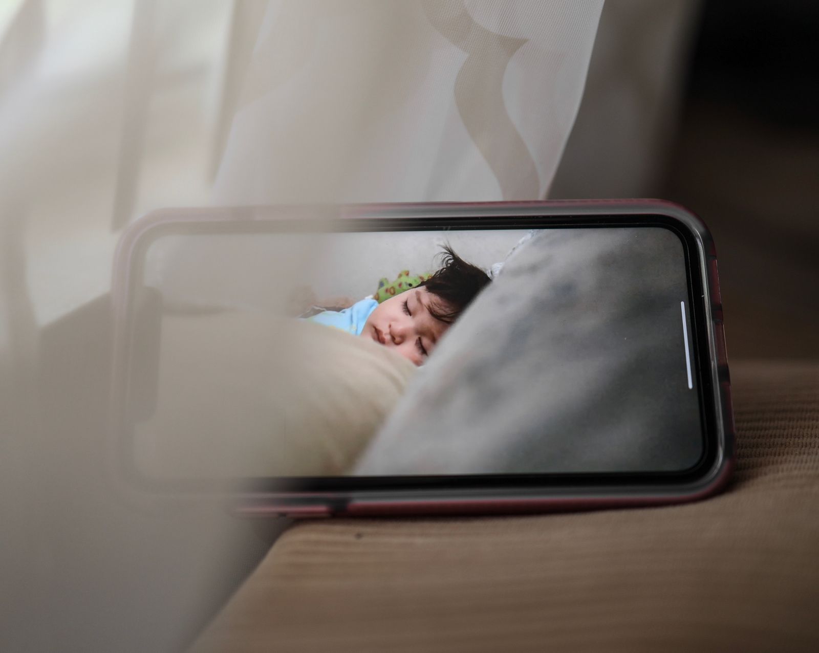 Remote baby monitor view showing a sleeping child on a screen