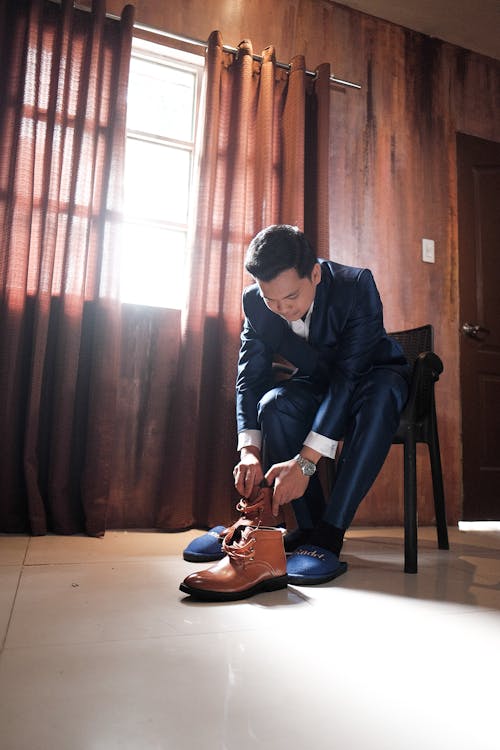 Man in elegant suit putting boots