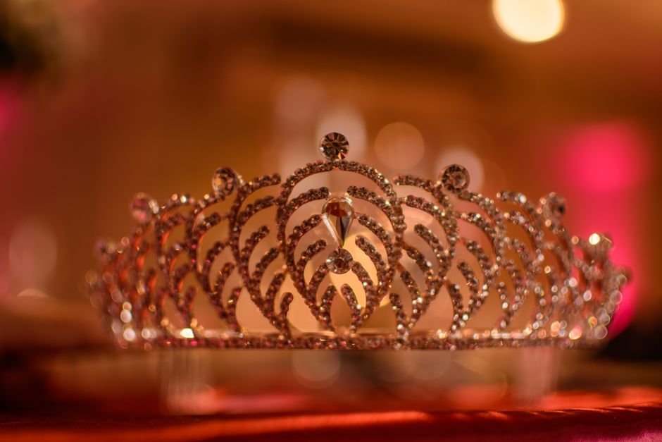 A beautifully detailed crystal crown glistening under warm, soft lighting in an elegant setting.