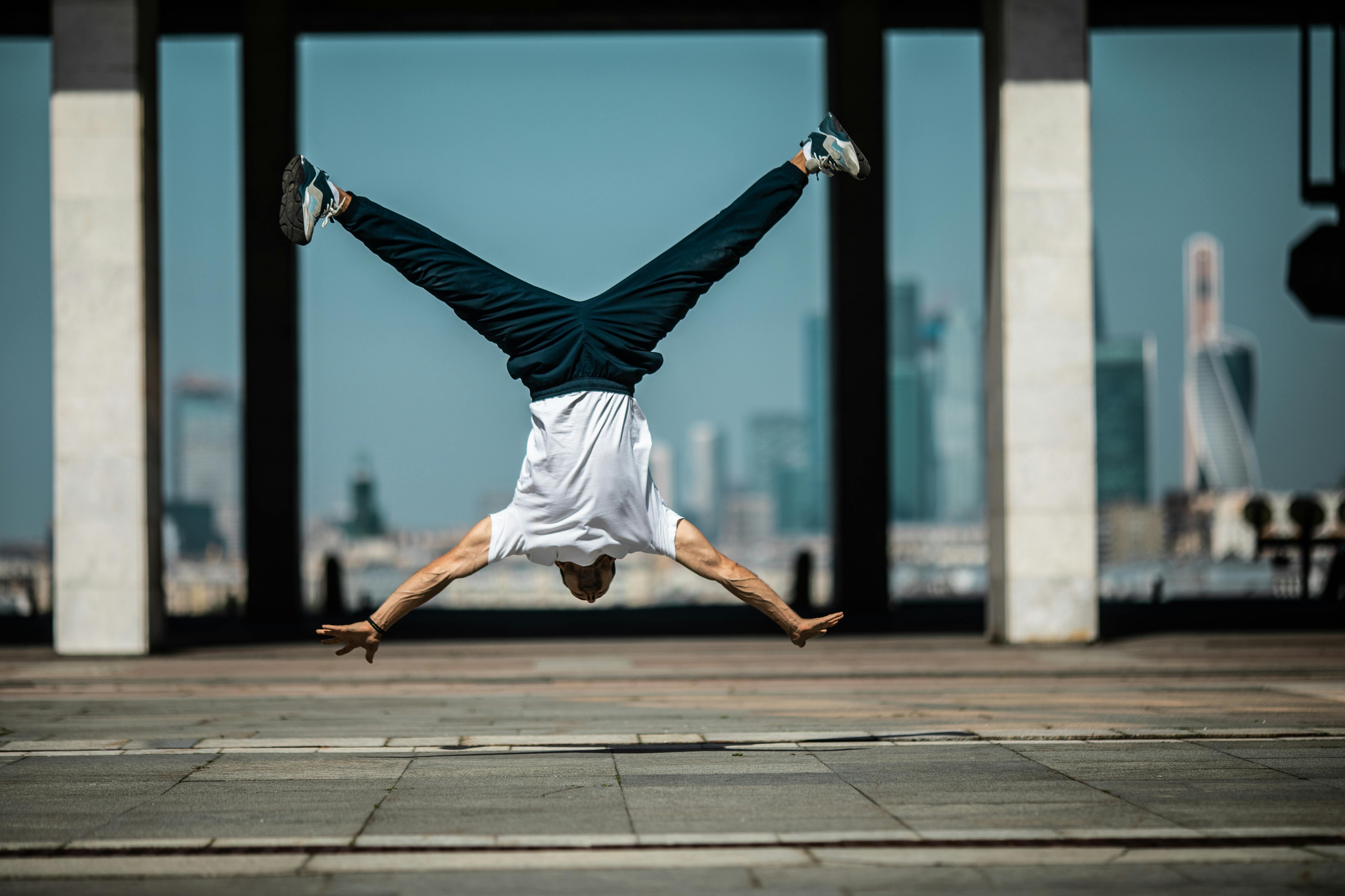 a man in white shirt and blue pants in upside down position